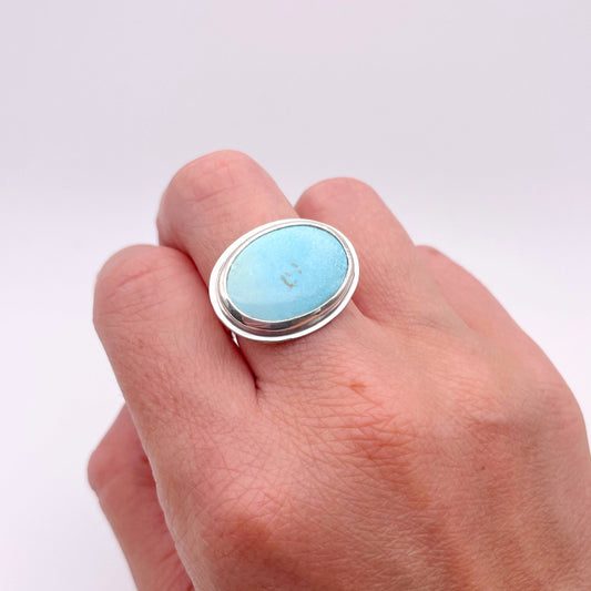 Hand wearing a ring with a blue stone on a white background