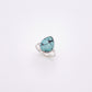 A silver ring featuring a teardrop-shaped turquoise stone with dark matrix veining, set against a plain white background.