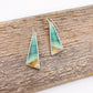Teal and gold triangle-shaped earrings on a wooden surface