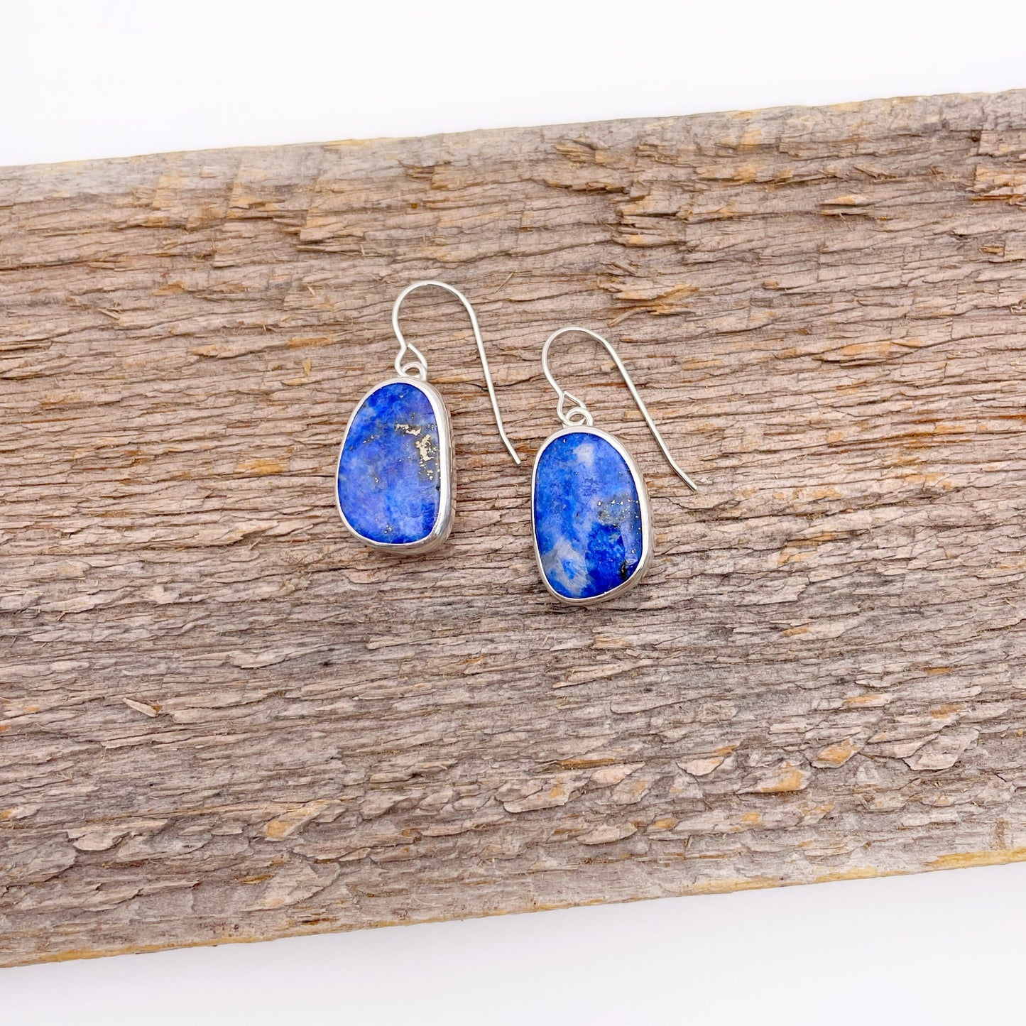 Pair of blue stone earrings on a wooden surface