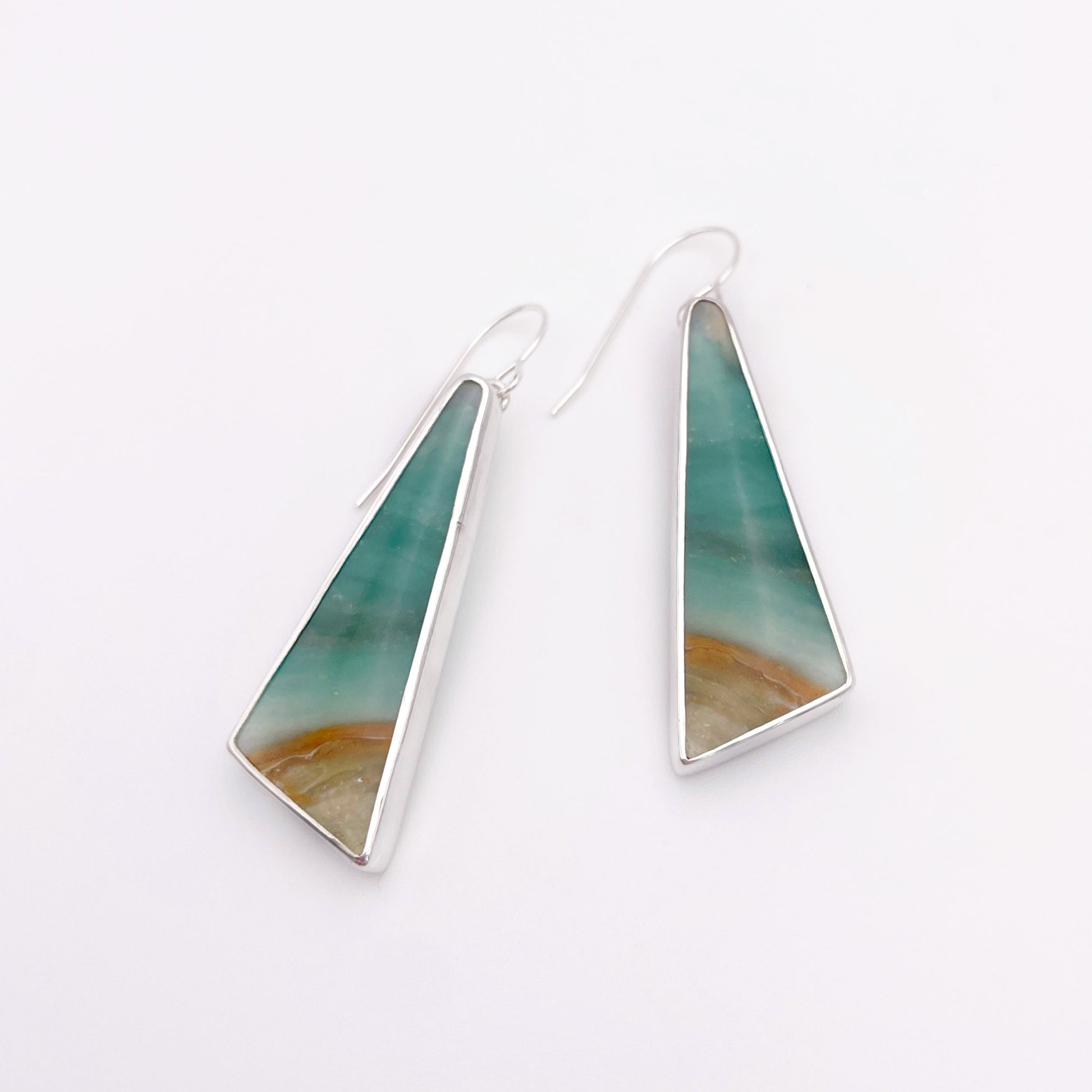 Triangular earrings with a green and brown design on a white background